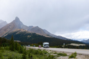 Wohnmobil und Autos auf dem Icefields Parkway vor markanten Felsgipfeln der kanadischen Rocky Mountains